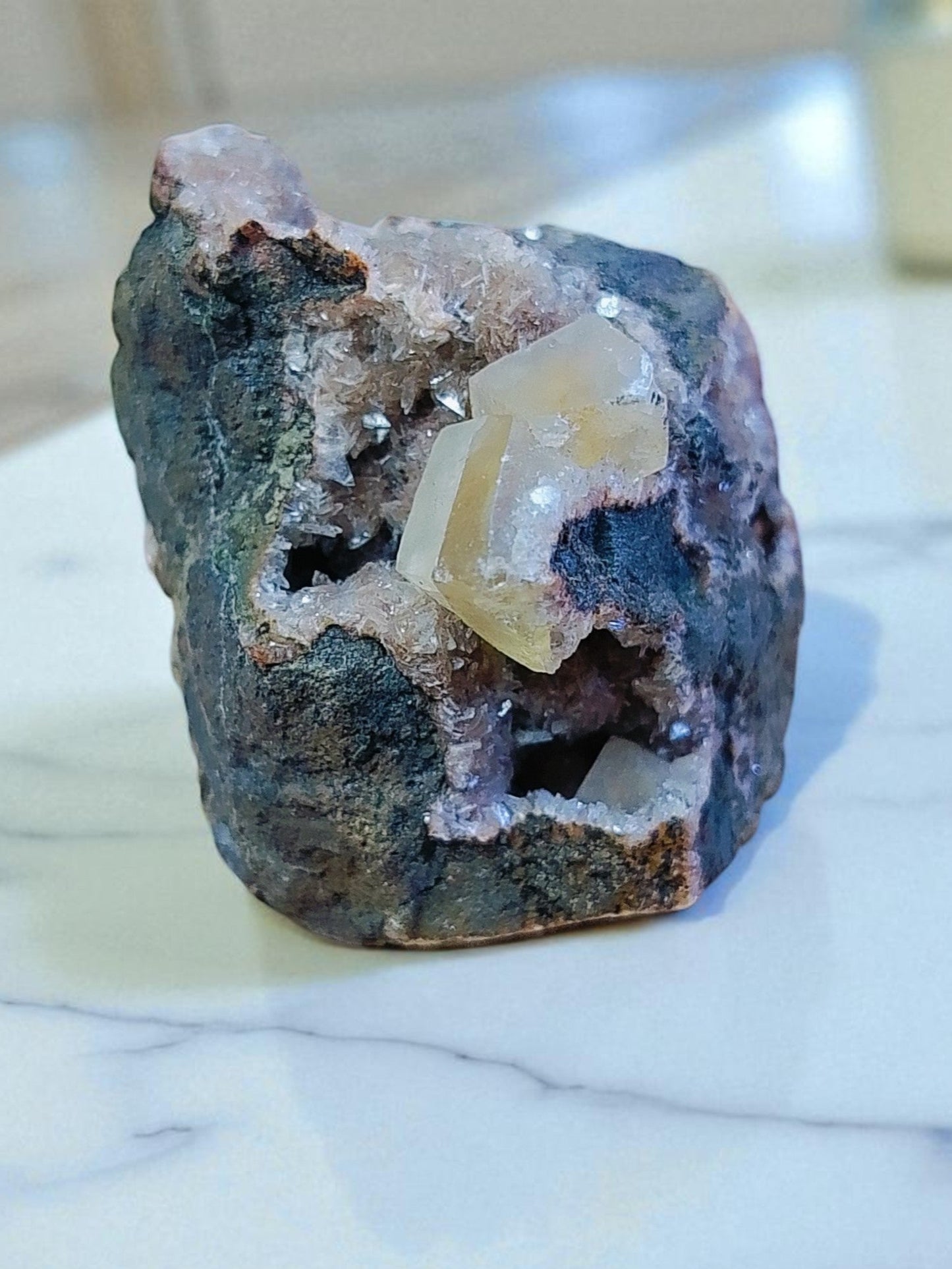 Mineral sample with a clear crystal on a marble surface